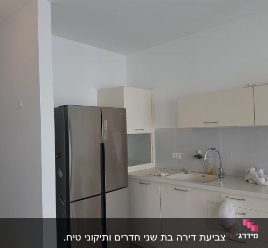 מטבח עם קיר צבוע בלבן, כיור וברז